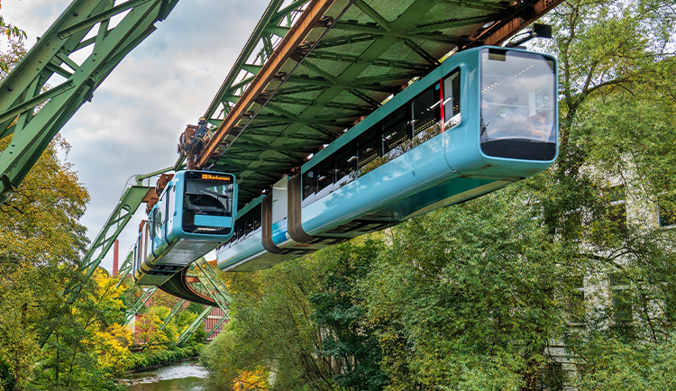 Abbildung Bild- und Wertseite der Münze „125 Jahre Wuppertaler Schwebebahn“ sowie Fotografie einer fahrenden Schwebebahn